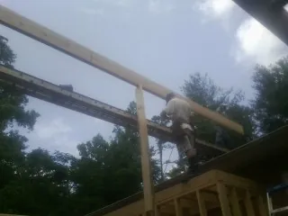 Carpenter setting a ridge beam over a new addition frame — Ice Dam Removal by Roofing Brothers in Hortense