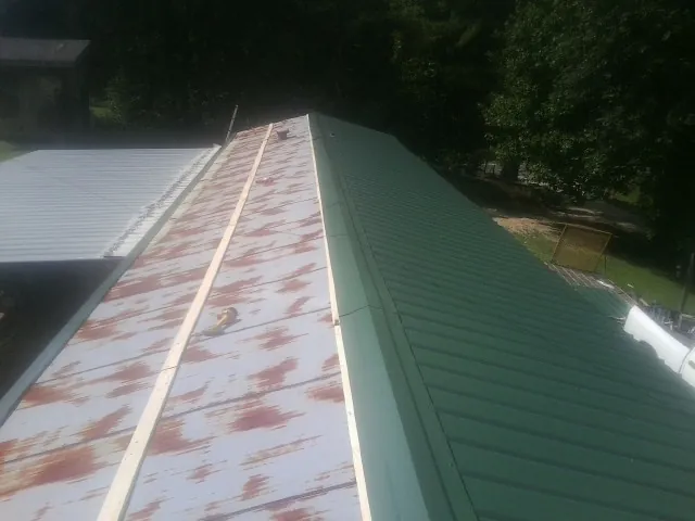 Old rusted panels beside newly installed green metal roofing — Wind Damage Roof Repair by Roofing Brothers in Hortense