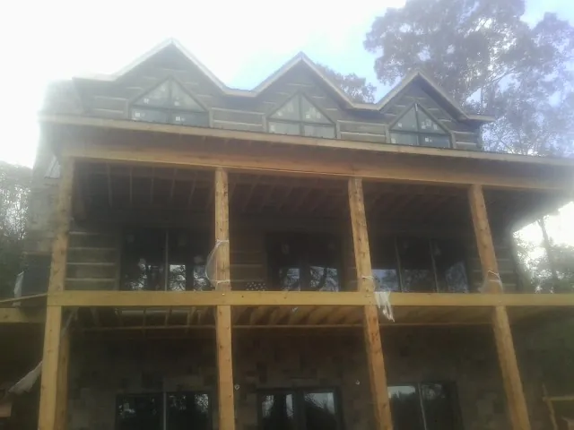 Dormers and porch framing on a large log home under construction — Roof Coating work by our crew in Hortense