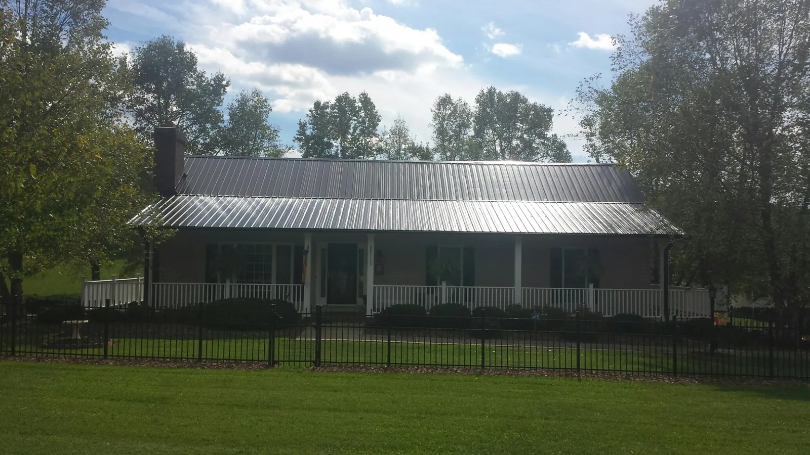 Gray metal roof on a brick ranch with a full width front porch — Gutter Guard Installation work by our crew in Hortense