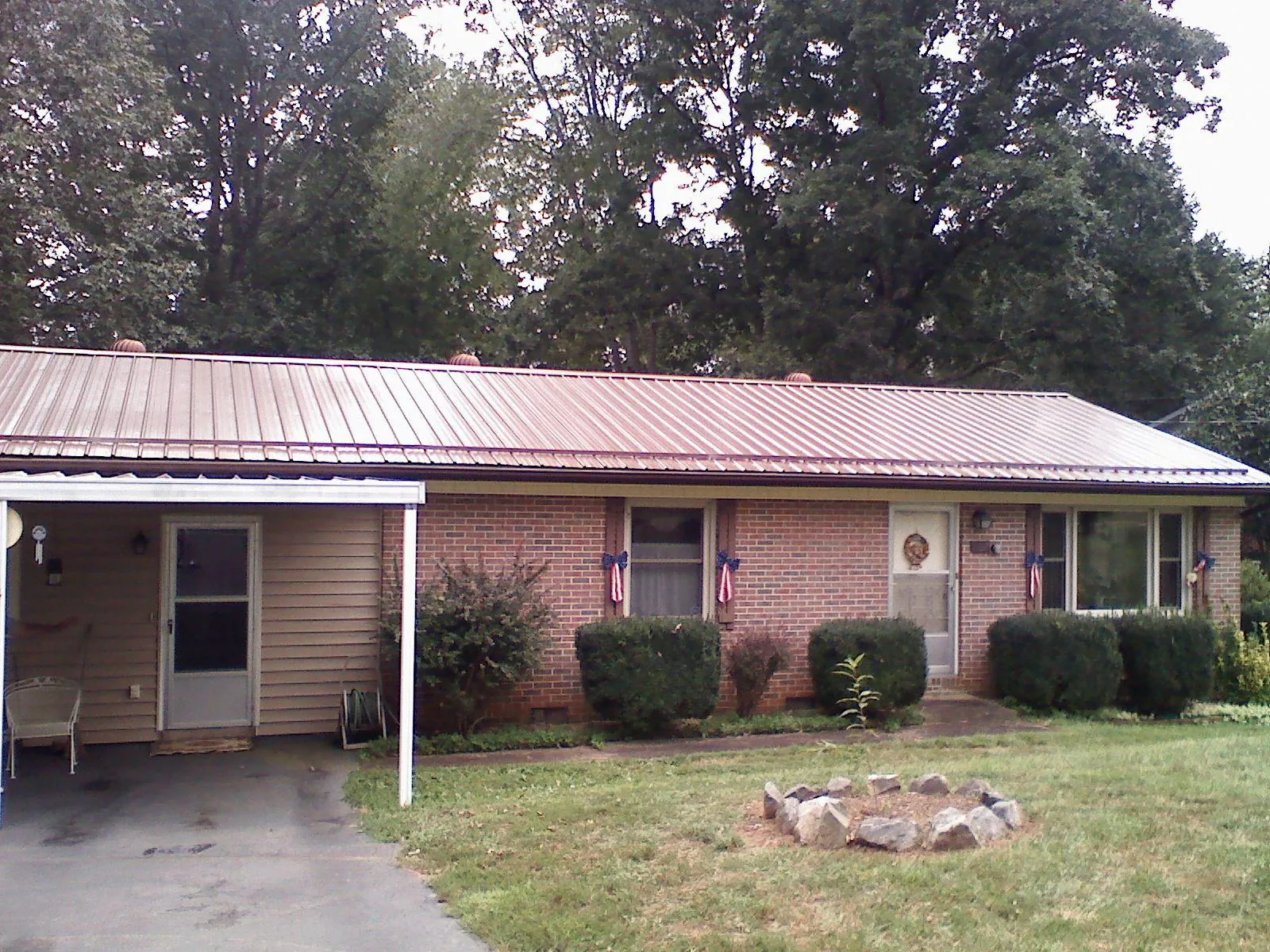 Bronze metal roof and carport on a brick ranch home — Roof Repair work by our crew in Hortense