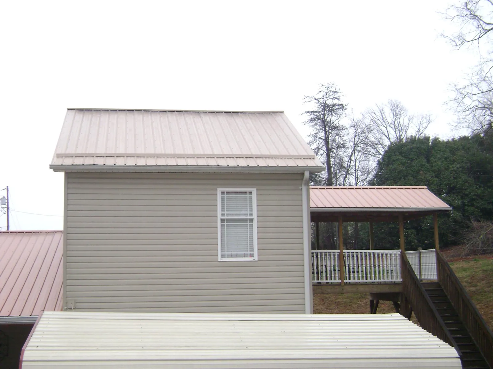 Tan metal roofs on a two story addition and attached porch, from a Roof Replacement job in Hortense