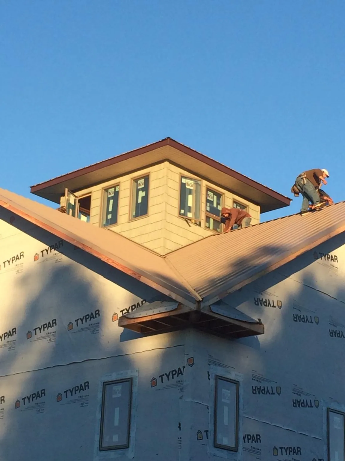 Roofers working around a rooftop cupola on a new metal roof at sunset — Roof Waterproofing in Hortense by Roofing Brothers
